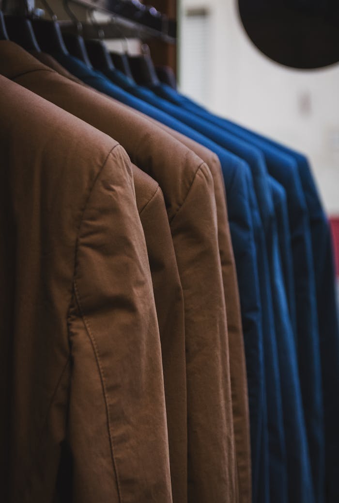Home Showcase of neatly arranged brown and blue jackets on hangers, emphasizing fashion and style.